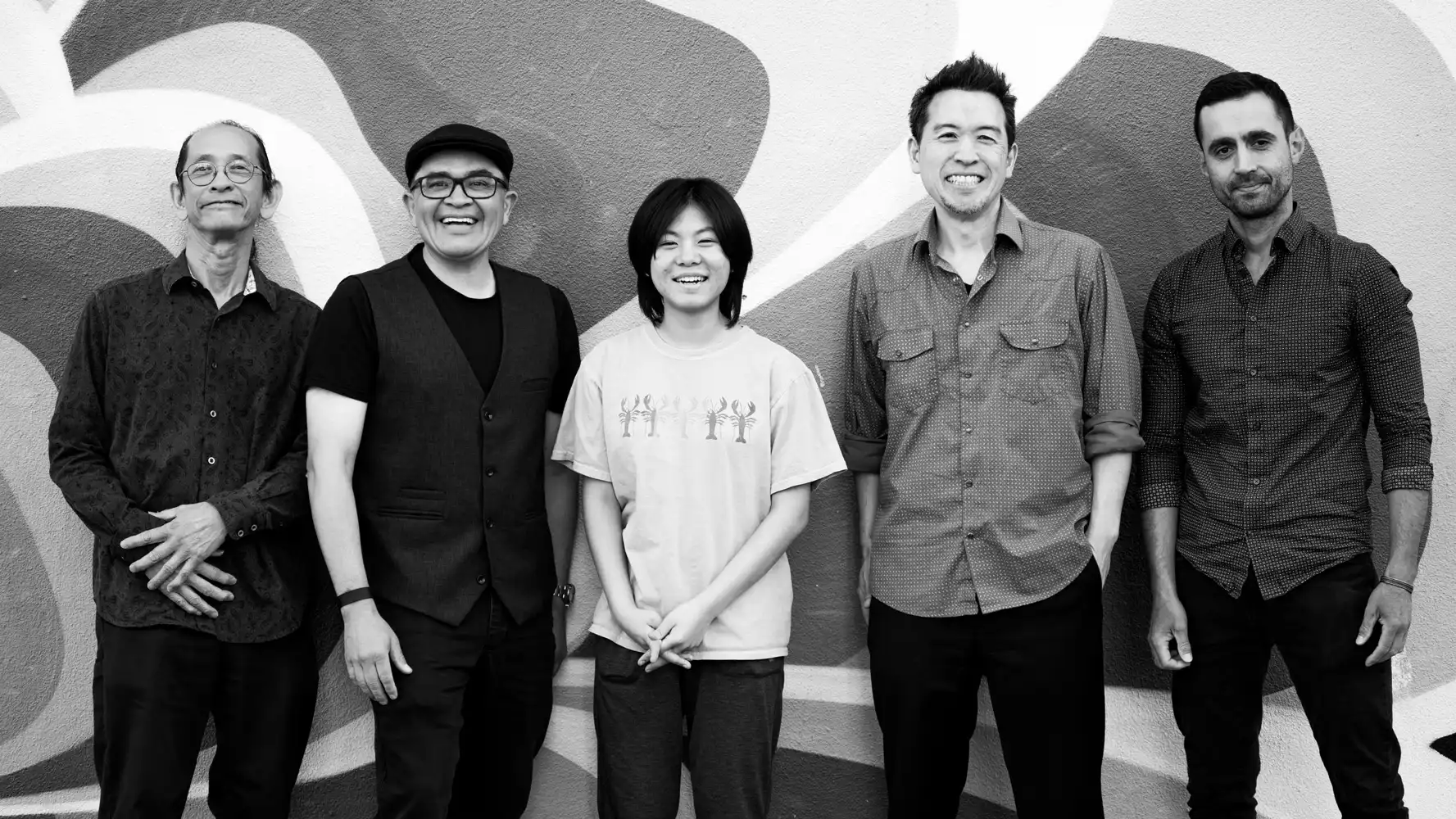 Ken Okada Group ft. YOYOKA standing together in black and white against a mural wall